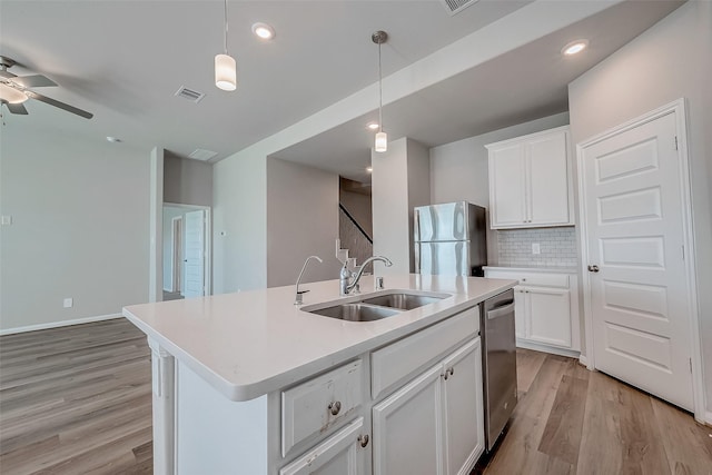 kitchen featuring a center island with sink, hanging light fixtures, sink, appliances with stainless steel finishes, and white cabinetry