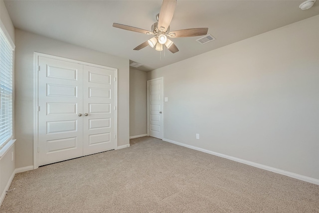 unfurnished bedroom with ceiling fan, light colored carpet, and a closet