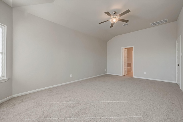 empty room featuring light carpet, vaulted ceiling, a wealth of natural light, and ceiling fan