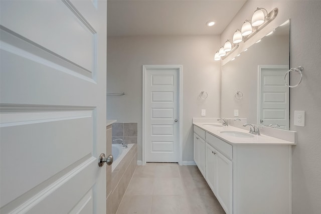 bathroom with tiled tub, tile patterned flooring, and vanity