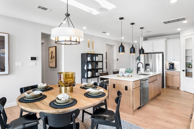 dining area featuring light hardwood / wood-style floors, an inviting chandelier, and sink