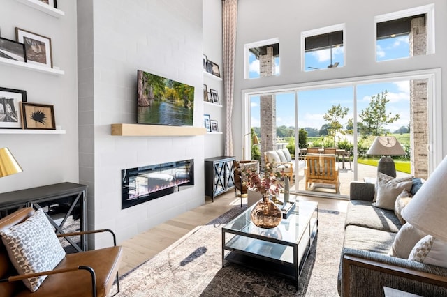 living room with hardwood / wood-style flooring, a large fireplace, and a high ceiling