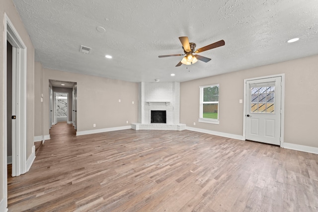 unfurnished living room featuring a fireplace, hardwood / wood-style floors, a textured ceiling, and ceiling fan