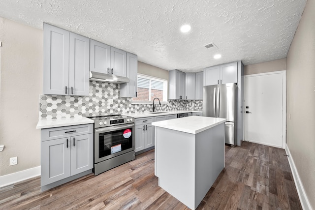 kitchen with sink, a center island, a textured ceiling, and stainless steel appliances