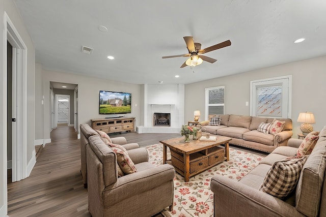 living room with ceiling fan, hardwood / wood-style floors, and a large fireplace