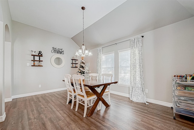 dining space with wood-type flooring, vaulted ceiling, and a notable chandelier