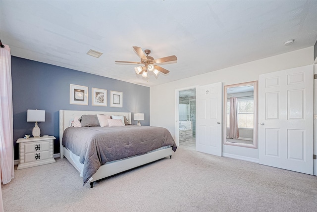 carpeted bedroom with ensuite bath and ceiling fan