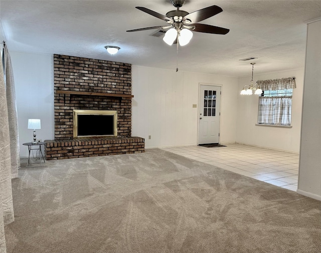 unfurnished living room with a textured ceiling, ceiling fan with notable chandelier, light carpet, and a brick fireplace