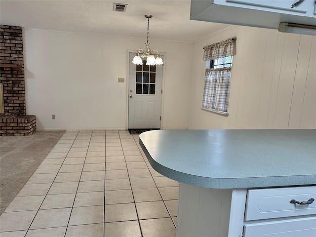 unfurnished dining area with a brick fireplace, a textured ceiling, light colored carpet, and an inviting chandelier