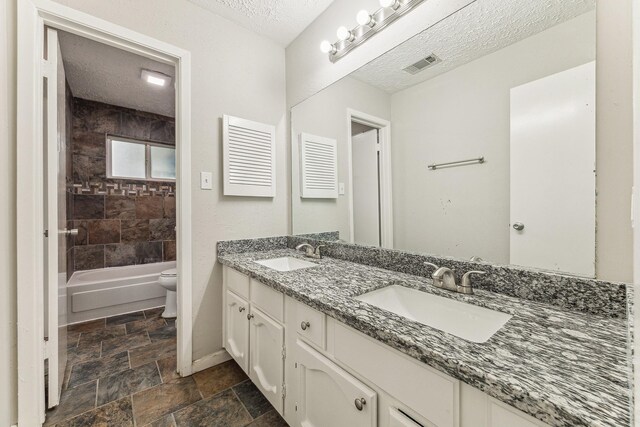 full bathroom featuring vanity, tiled shower / bath combo, a textured ceiling, and toilet