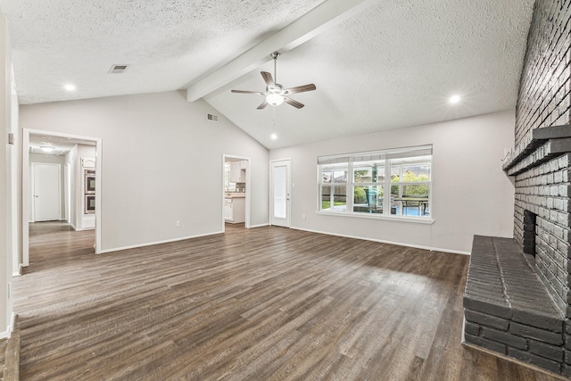 unfurnished living room featuring dark wood-type flooring, lofted ceiling with beams, ceiling fan, a textured ceiling, and a fireplace