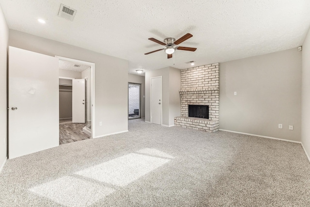 unfurnished living room with light carpet, a textured ceiling, a brick fireplace, and ceiling fan