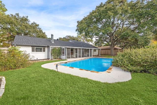 view of swimming pool featuring a sunroom and a yard