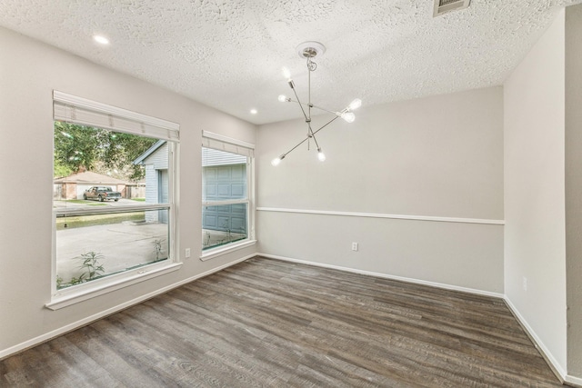 unfurnished room featuring dark hardwood / wood-style floors, a textured ceiling, and a chandelier