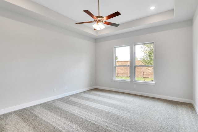 unfurnished room with a tray ceiling, ceiling fan, and carpet floors