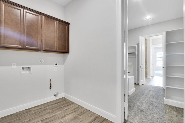 clothes washing area with cabinets, hookup for a gas dryer, hookup for a washing machine, light wood-type flooring, and hookup for an electric dryer