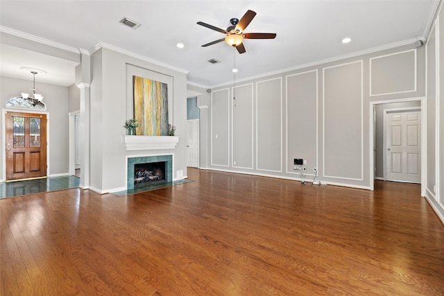 unfurnished living room featuring ceiling fan with notable chandelier, a premium fireplace, dark wood-type flooring, and ornamental molding