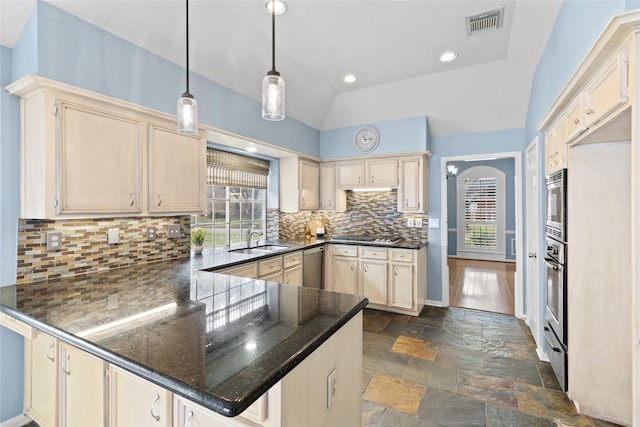 kitchen featuring lofted ceiling, hanging light fixtures, tasteful backsplash, kitchen peninsula, and stainless steel appliances