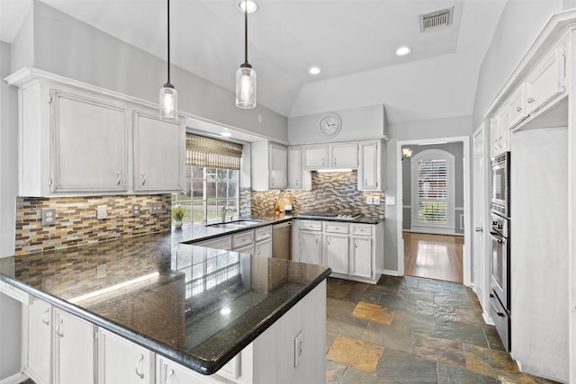 kitchen with kitchen peninsula, white cabinets, decorative light fixtures, and vaulted ceiling