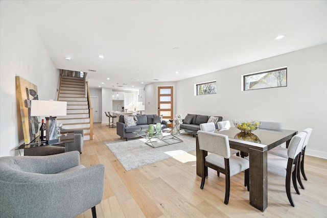 living area featuring stairs, light wood finished floors, baseboards, and recessed lighting