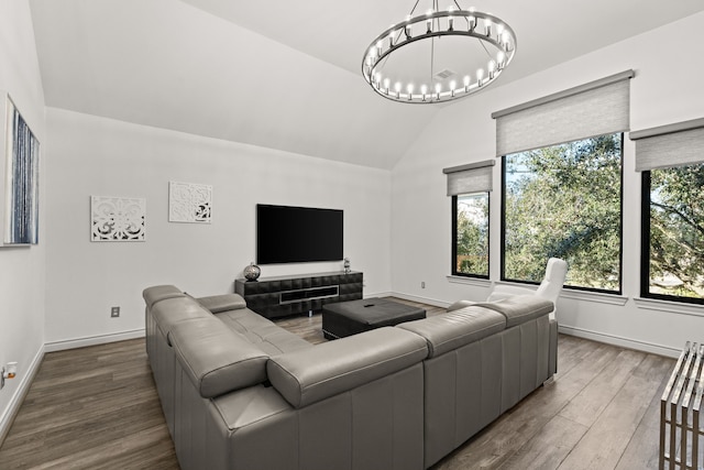 living room featuring a notable chandelier, wood-type flooring, and vaulted ceiling