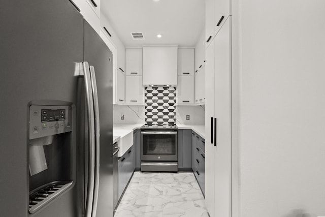 kitchen with stainless steel appliances, white cabinetry, custom range hood, and tasteful backsplash