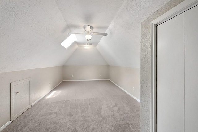 bonus room with ceiling fan, carpet floors, lofted ceiling with skylight, and a textured ceiling