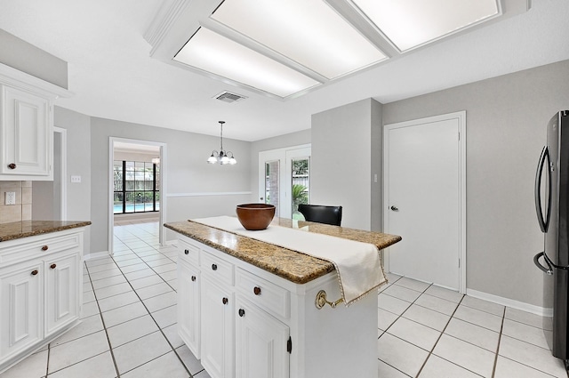 kitchen featuring stainless steel fridge, white cabinetry, a center island, and a healthy amount of sunlight