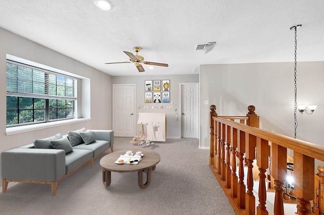 carpeted living room featuring ceiling fan and a textured ceiling