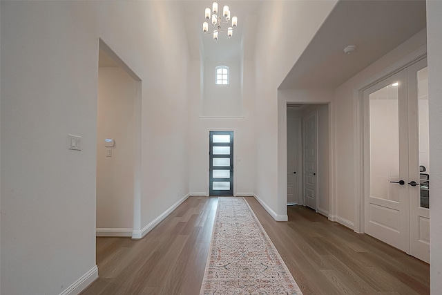 foyer with light hardwood / wood-style flooring, a towering ceiling, and an inviting chandelier