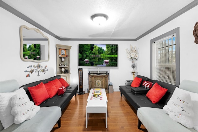 living room with light hardwood / wood-style floors, a textured ceiling, and ornamental molding