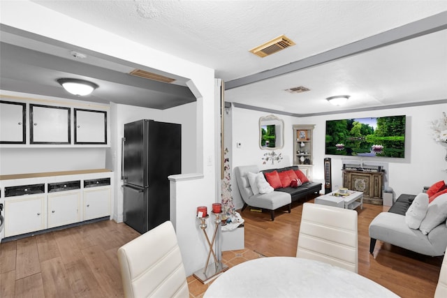 living room with ornamental molding, a textured ceiling, and light hardwood / wood-style flooring