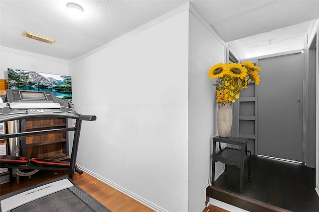 interior space with hardwood / wood-style flooring, ornamental molding, and a textured ceiling