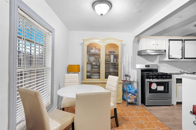 kitchen featuring a textured ceiling, white cabinetry, light hardwood / wood-style flooring, and stainless steel gas range