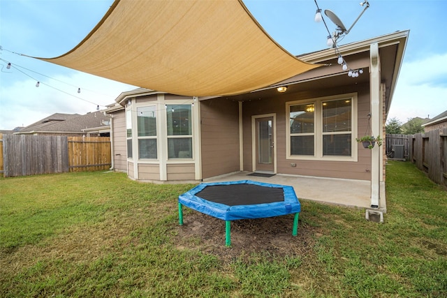 back of property featuring a lawn, central air condition unit, and a trampoline