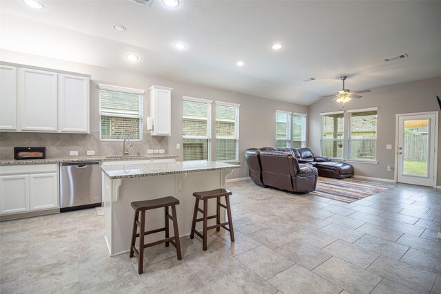 kitchen with dishwasher, a kitchen island, white cabinetry, and vaulted ceiling