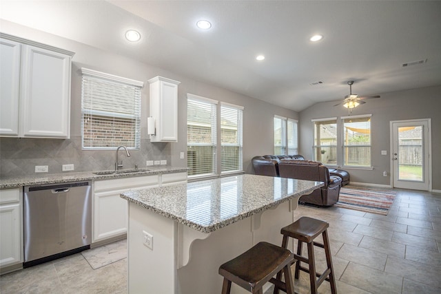 kitchen featuring lofted ceiling, sink, stainless steel dishwasher, tasteful backsplash, and white cabinetry