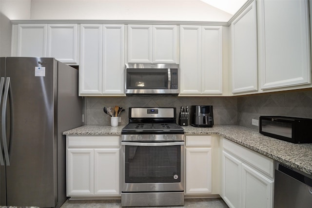 kitchen with decorative backsplash, stainless steel appliances, white cabinetry, and light stone counters