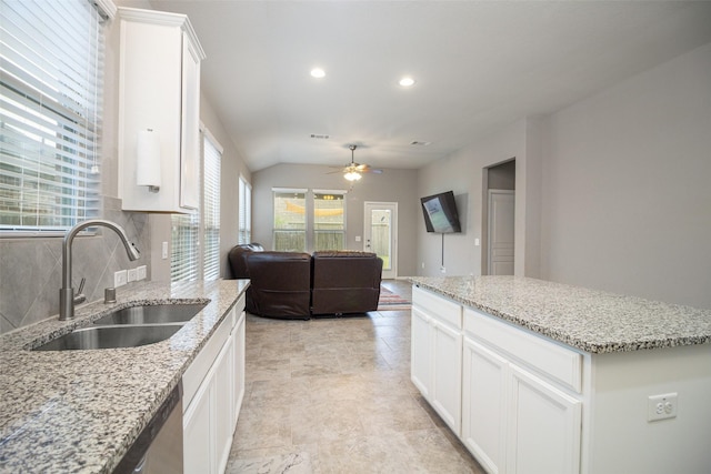 kitchen featuring white cabinetry, sink, ceiling fan, light stone counters, and decorative backsplash