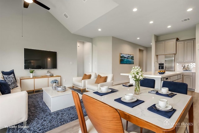 dining area featuring ceiling fan, lofted ceiling, and light wood-type flooring