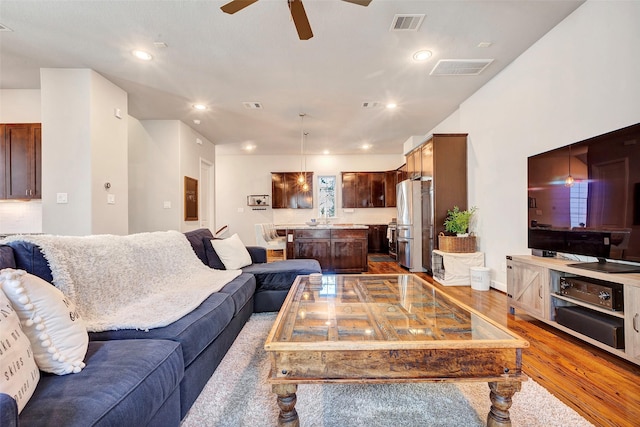 living room featuring hardwood / wood-style floors, ceiling fan, and sink