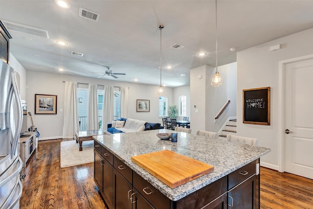 kitchen featuring dark brown cabinetry, ceiling fan, hanging light fixtures, dark hardwood / wood-style flooring, and a kitchen island