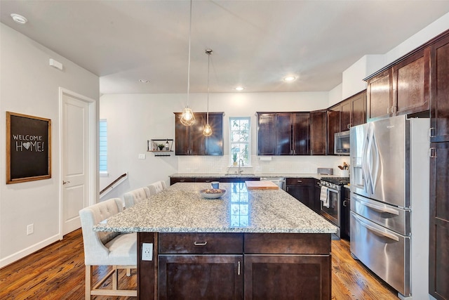 kitchen with a breakfast bar, decorative light fixtures, a center island, and stainless steel appliances