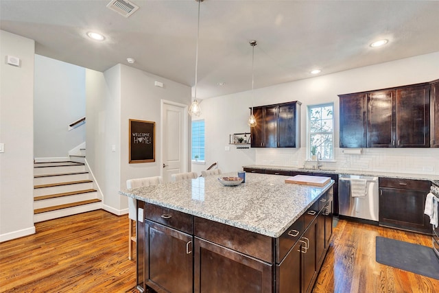 kitchen featuring dishwasher, backsplash, decorative light fixtures, dark brown cabinets, and a kitchen island