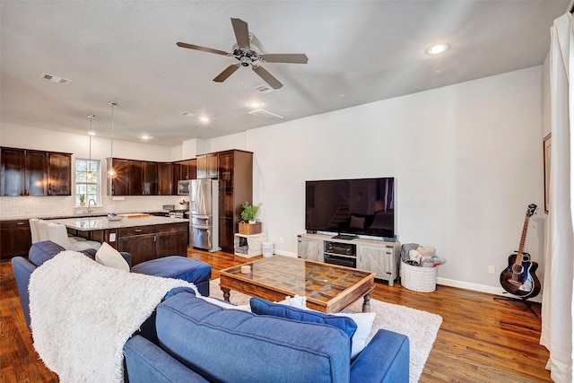 living room with ceiling fan, dark wood-type flooring, and sink