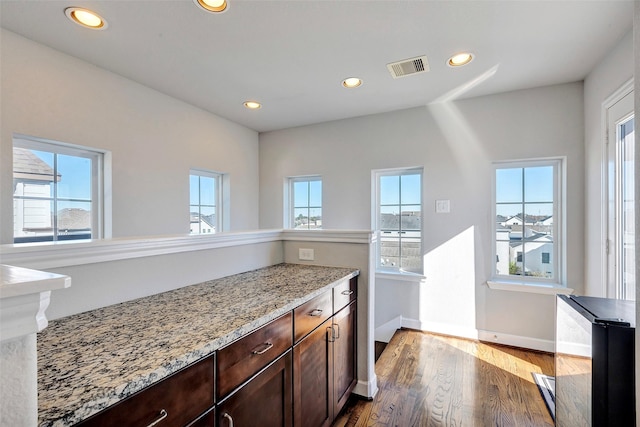 kitchen featuring dark hardwood / wood-style floors, dark brown cabinetry, and light stone countertops