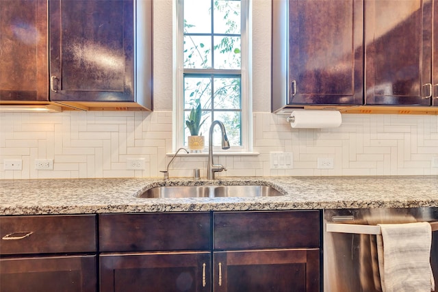 kitchen featuring backsplash, light stone countertops, and sink