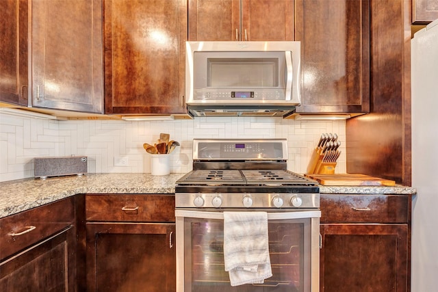 kitchen with light stone counters, stainless steel range with gas cooktop, and tasteful backsplash