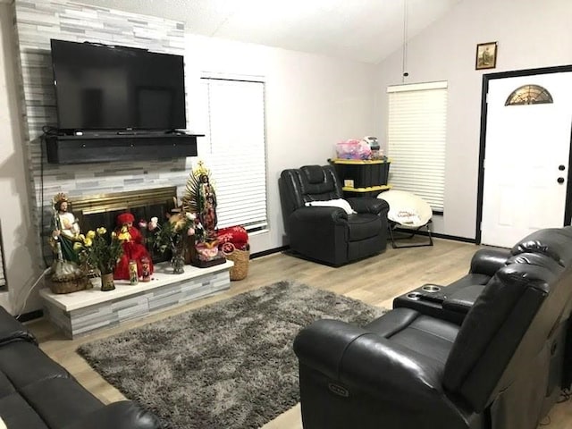 living room featuring light hardwood / wood-style floors, lofted ceiling, and a tiled fireplace