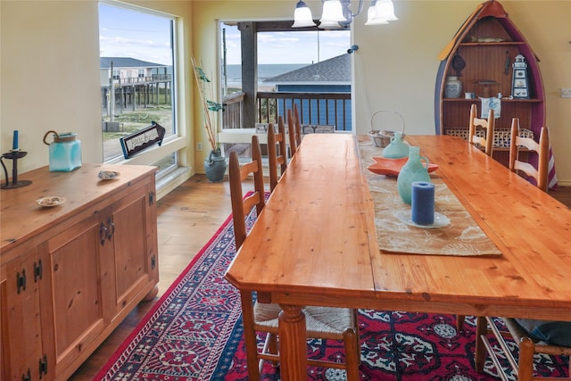 dining room featuring a chandelier, light hardwood / wood-style floors, and a water view